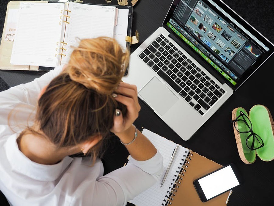 Woman leaning forward to rest her head in her hands braced on a table. She is surrounded by office paraphernalia like a laptop, notebook, and cell phone.
Business Systems can ease work frustration.