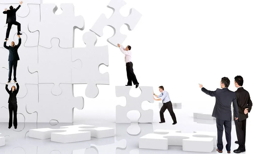 Two people in business attire are acts as managers to a group of other people in business attire as they move white puzzle pieces as tall as they are into place with the puzzle stand straight up. Three people are standing on top of each other so that the top person can reach a puzzle piece high up. The other two people are also helping each other, with the one on the ground pushing a puzzle piece into place with the other standing on top of that piece placing his piece in a higher position. (ie. example of team work and management)

Having a prepared business crisis management plan can help make putting things back together easier.